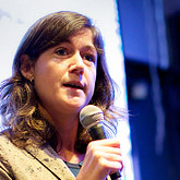 Woman speaking into a microphone in front of a screen