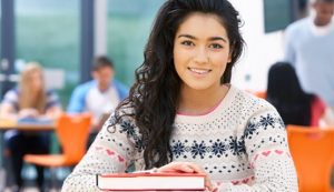 Smiling female student with her hand on top of a book
