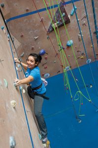 Young female student climbing a climbing wall