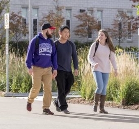 Three students, two male, one female, walking together outside