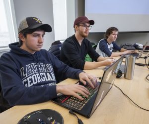 Three male students participate in computer science class