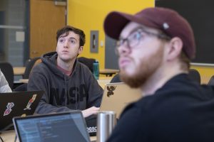 Two male students looking up at instructor in computer science class